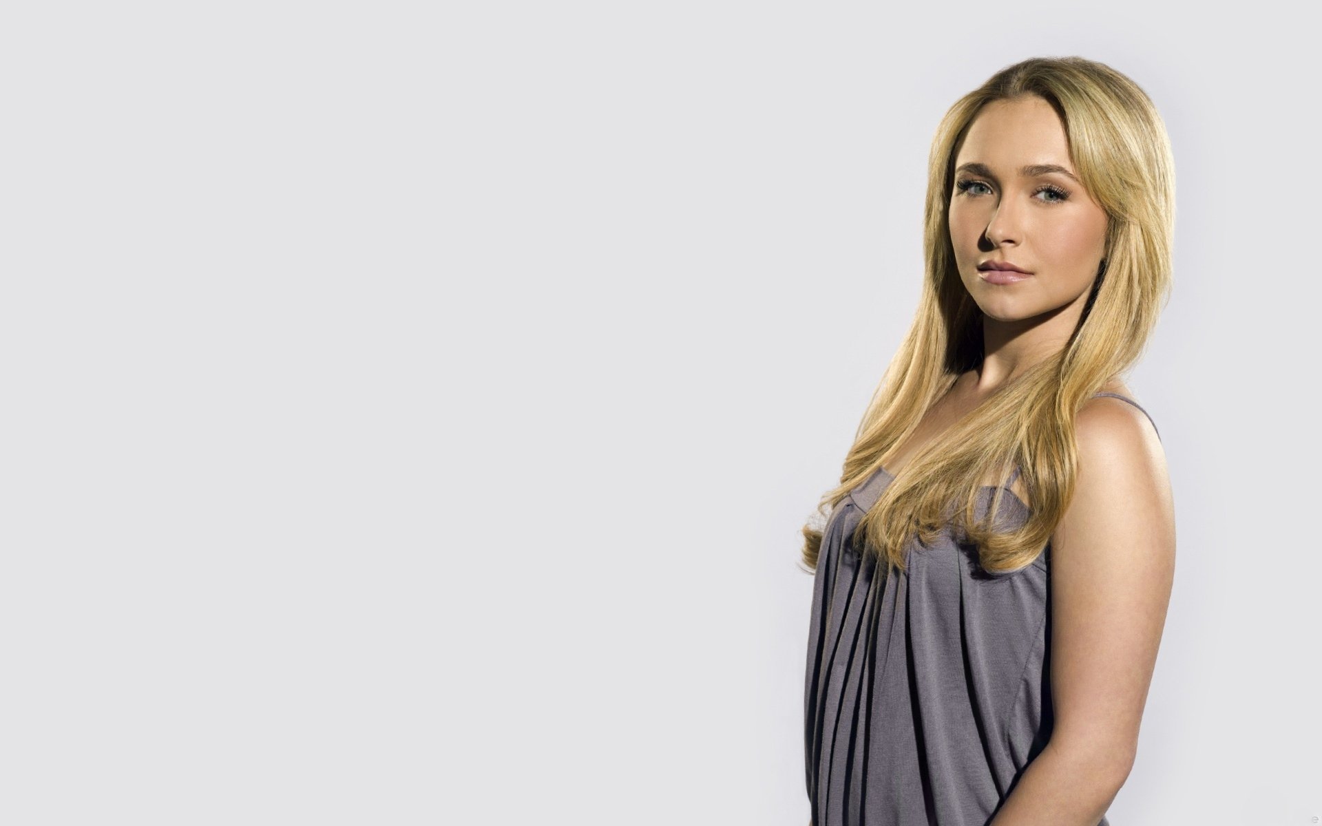 HD PC desktop wallpaper featuring celebrity Hayden Panettiere standing against a plain light background, wearing a sleeveless gray top.