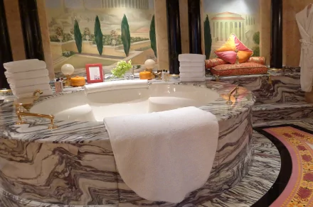 Luxurious man-made spa with a large marble Jacuzzi tub, neatly stacked towels, and elegant decor, captured in HD for a PC desktop wallpaper background.