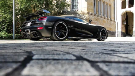 A sleek black Koenigsegg Agera R is parked in front of a historic building, captured in HD detail as a stunning desktop wallpaper background.