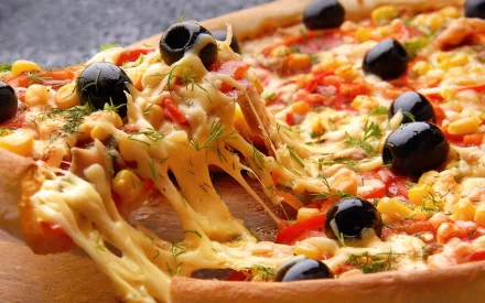 HD PC desktop wallpaper featuring a close-up of a cheesy pizza topped with black olives, corn, and herbs, capturing vibrant food details in high definition.