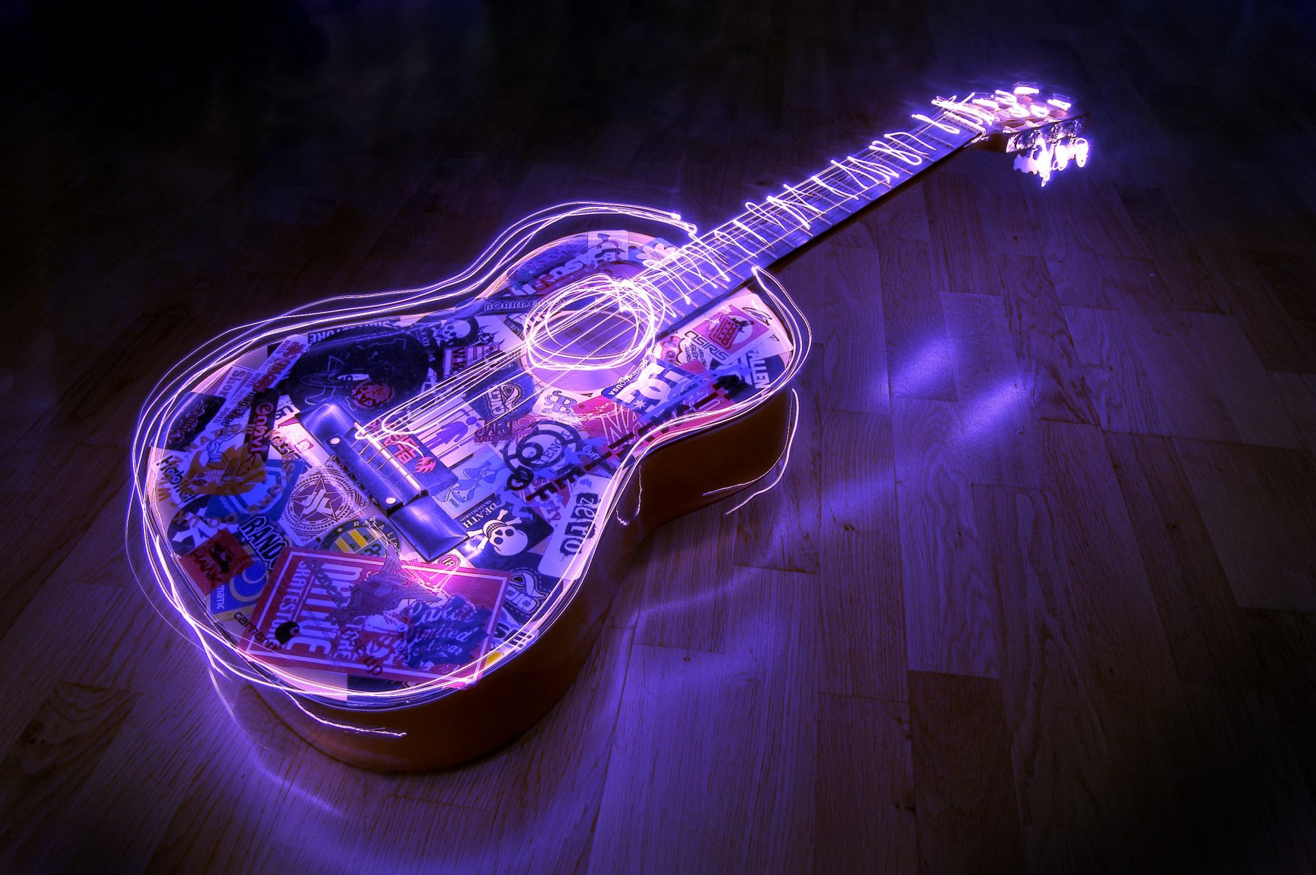 A vibrant guitar illuminated with colorful light effects, resting on a wooden floor, serves as an engaging HD desktop wallpaper and background for music enthusiasts.