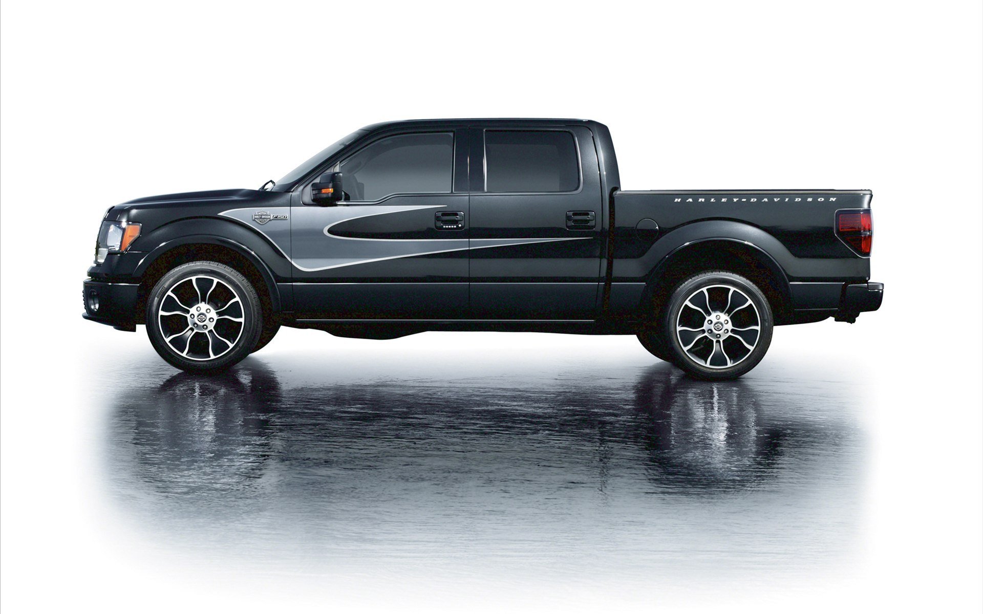 Side view of a black 2012 Ford Harley Davidson F-150 truck, showcased on a reflective surface as an HD PC desktop wallpaper and background.