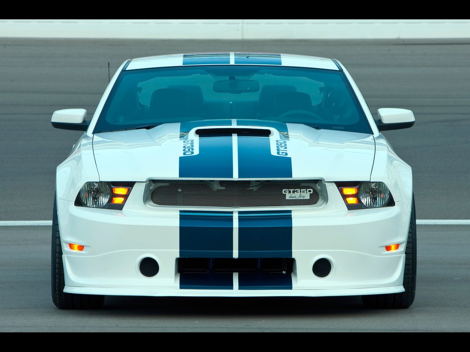 Front view of a white Ford Mustang Shelby with blue racing stripes on a racetrack, featured as an HD PC desktop wallpaper and background.
