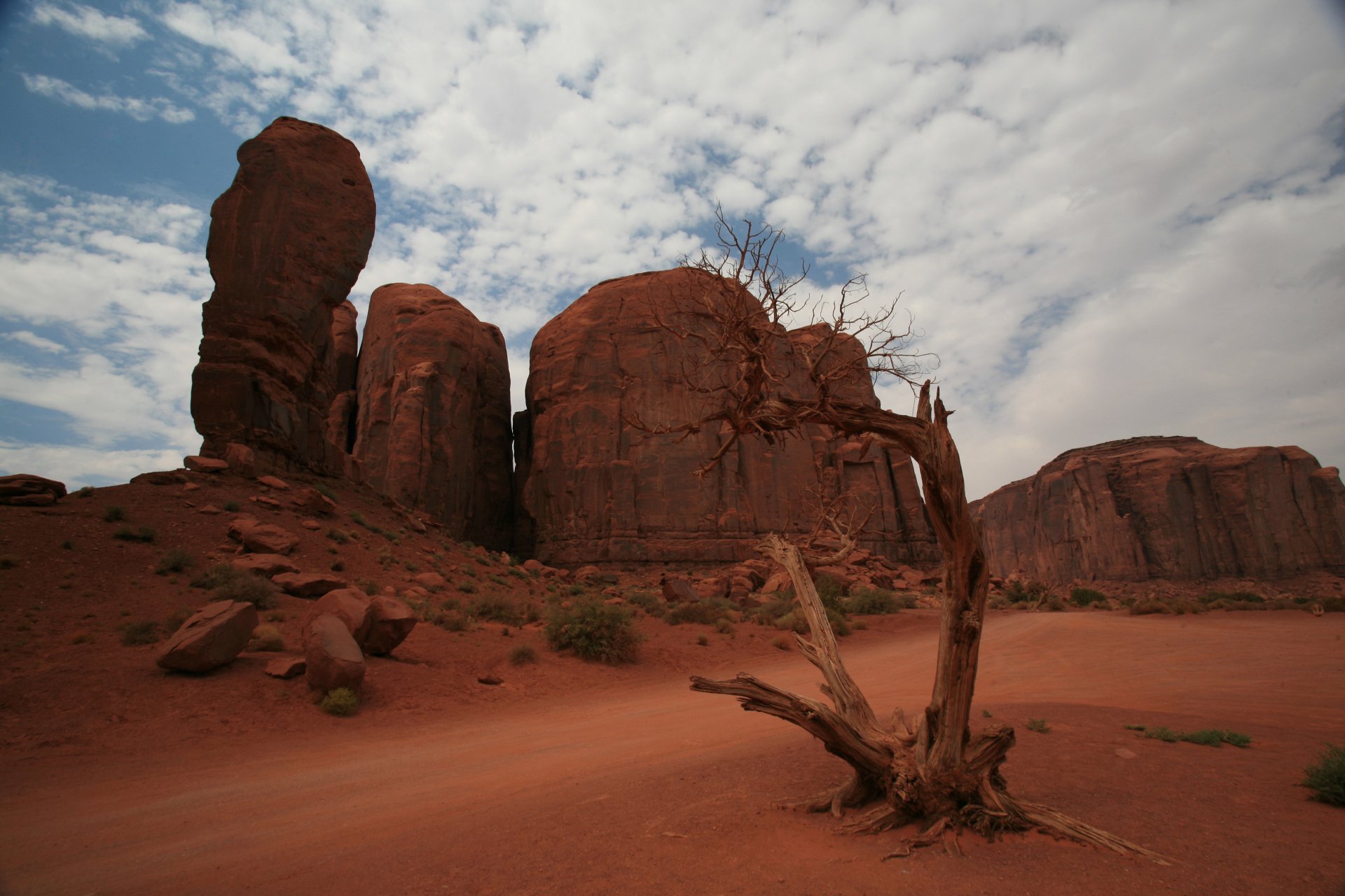 A striking 4K Ultra HD desktop wallpaper showcasing a rugged canyon landscape with towering red rock formations under a partly cloudy sky.
