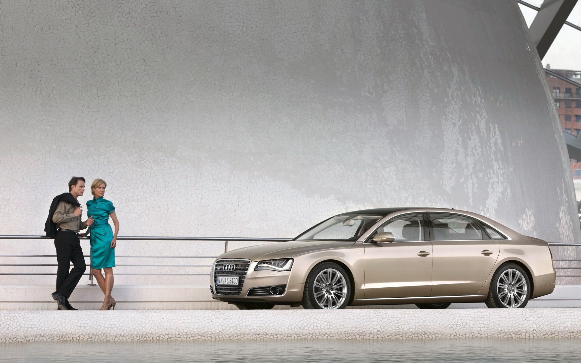 HD PC desktop wallpaper featuring a sleek Audi A8 parked near a modern architectural structure with two people standing nearby.