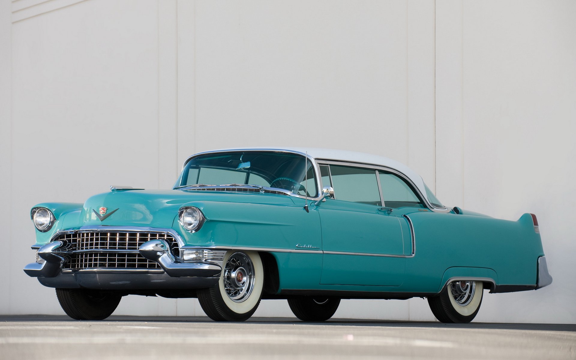 1955 Cadillac Sixty-Two in turquoise with whitewall tires on a pale backdrop — HD PC desktop wallpaper background.