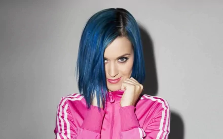 Katy Perry poses confidently in a vibrant pink outfit, showcasing her blue hair against a minimalist background. This HD wallpaper captures her energetic spirit in music.