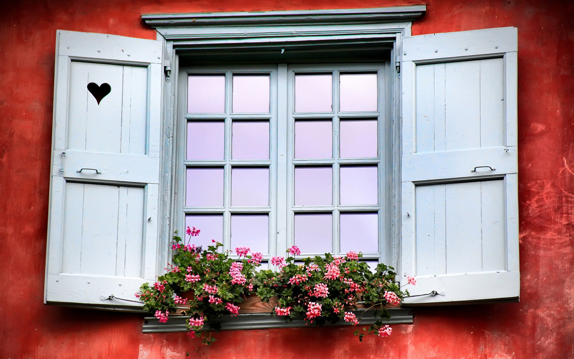 HD PC desktop wallpaper of a man-made white wooden window with shutters, a heart-shaped cutout, and pink flowers against a red textured wall.