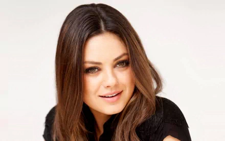 Mila Kunis poses gracefully, showcasing her signature style and captivating smile in this high-definition PC desktop wallpaper and background.