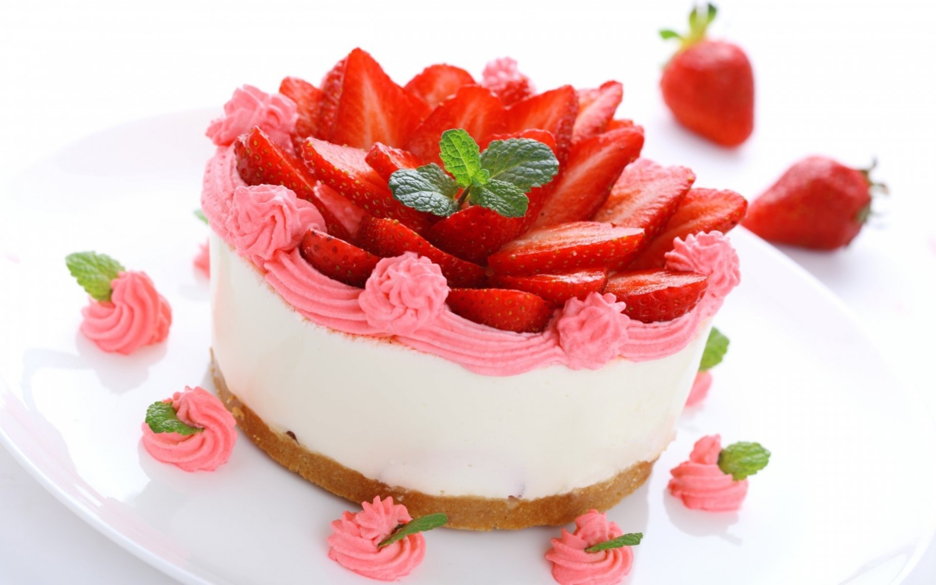A vibrant strawberry cake adorned with fresh strawberries and decorative pink frosting, presented on a white plate. This HD wallpaper captures the essence of delicious dessert.