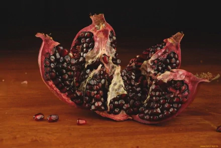 HD desktop wallpaper featuring a close-up of a split pomegranate with dark red seeds against a dark background, highlighting its rich texture and vibrant color.