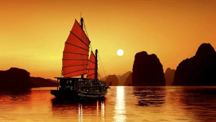A stunning sunset over Vietnam with a traditional junk boat sailing on calm waters, surrounded by dramatic rock formations silhouetted against the vibrant orange sky.