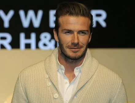 David Beckham poses in a stylish sweater against a backdrop featuring his name, showcasing his influence in sports and fashion. This HD image serves as an eye-catching desktop wallpaper.