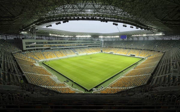 HD PC desktop wallpaper background: panoramic sports stadium interior, empty green pitch framed by yellow stands under a sweeping steel roof.