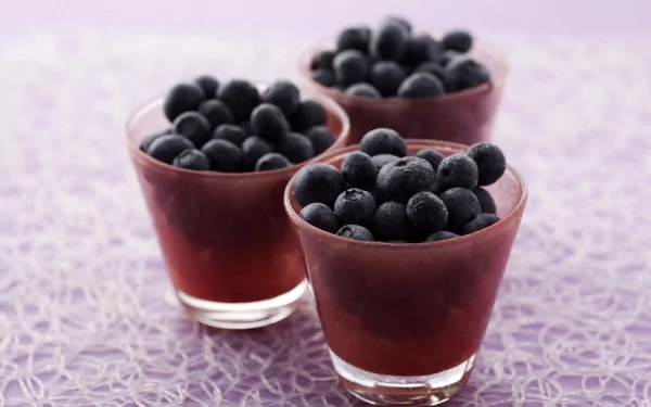 HD PC desktop wallpaper: three glass cups filled with blueberries on a lavender textured surface — food blueberry close-up background.