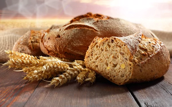 4K Ultra HD PC desktop wallpaper featuring rustic whole grain bread loaves and wheat stalks on a wooden surface with soft natural lighting.