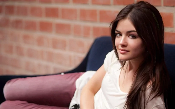 HD desktop wallpaper featuring celebrity Lucy Hale, relaxing on a couch against a brick wall background.