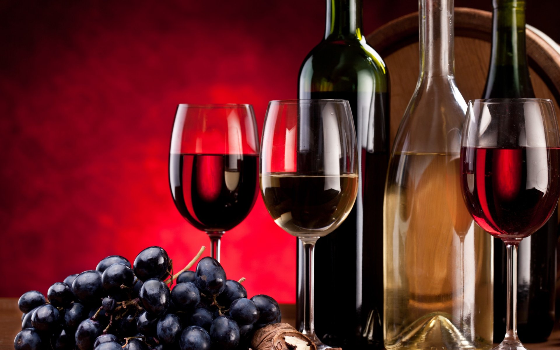 HD PC desktop wallpaper featuring red and white wine bottles with glasses and fresh grapes against a deep red background, highlighting food and wine themes.