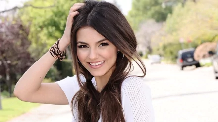HD desktop wallpaper featuring celebrity Victoria Justice smiling outdoors with natural light and greenery in the background.