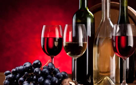 HD PC desktop wallpaper featuring red and white wine bottles with glasses and fresh grapes against a deep red background, highlighting food and wine themes.