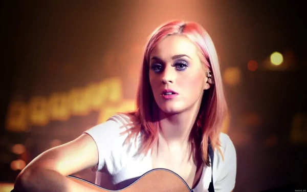 HD desktop wallpaper featuring Katy Perry with pink hair, playing a guitar amidst a soft-focus background with warm lighting. Tags: music, Katy Perry.