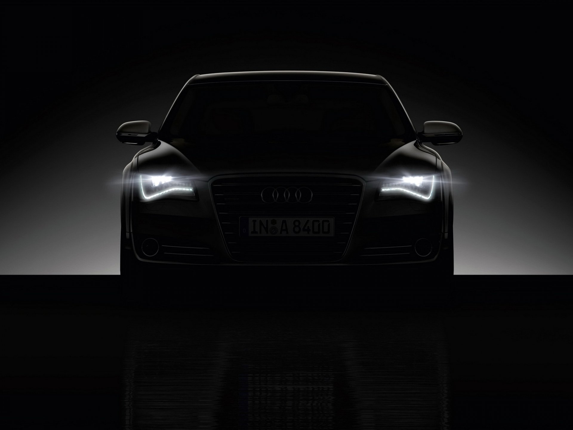 HD PC desktop wallpaper featuring a sleek Audi A8 with illuminated headlights against a dark background, highlighting the luxury vehicle's sharp front design.