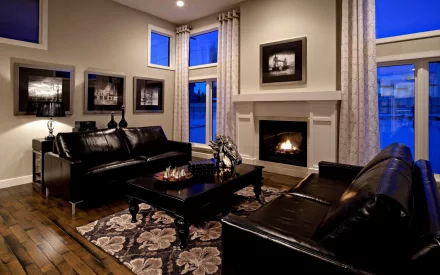 A stylish interior featuring a leather sofa and a cozy fireplace, surrounded by large windows and elegant decor, creating a warm and inviting atmosphere.