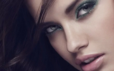 Close-up HD desktop wallpaper of celebrity Adriana Lima with striking green eye makeup and glossy lips.
