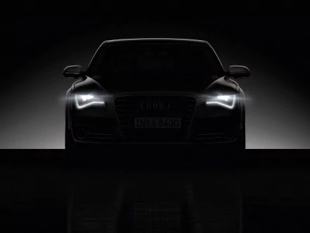 HD PC desktop wallpaper featuring a sleek Audi A8 with illuminated headlights against a dark background, highlighting the luxury vehicle's sharp front design.