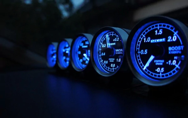 A close-up view of illuminated speedometer gauges in shades of blue, showcasing details and precision. This HD image serves as a striking desktop wallpaper and background.