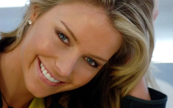 HD PC desktop wallpaper: close-up of a smiling blonde woman with wavy hair and green eyes, head tilted and resting on her hand, warm friendly expression.