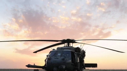 HD desktop wallpaper featuring a Sikorsky HH-60 Pave Hawk military helicopter silhouetted against a colorful sunset sky.