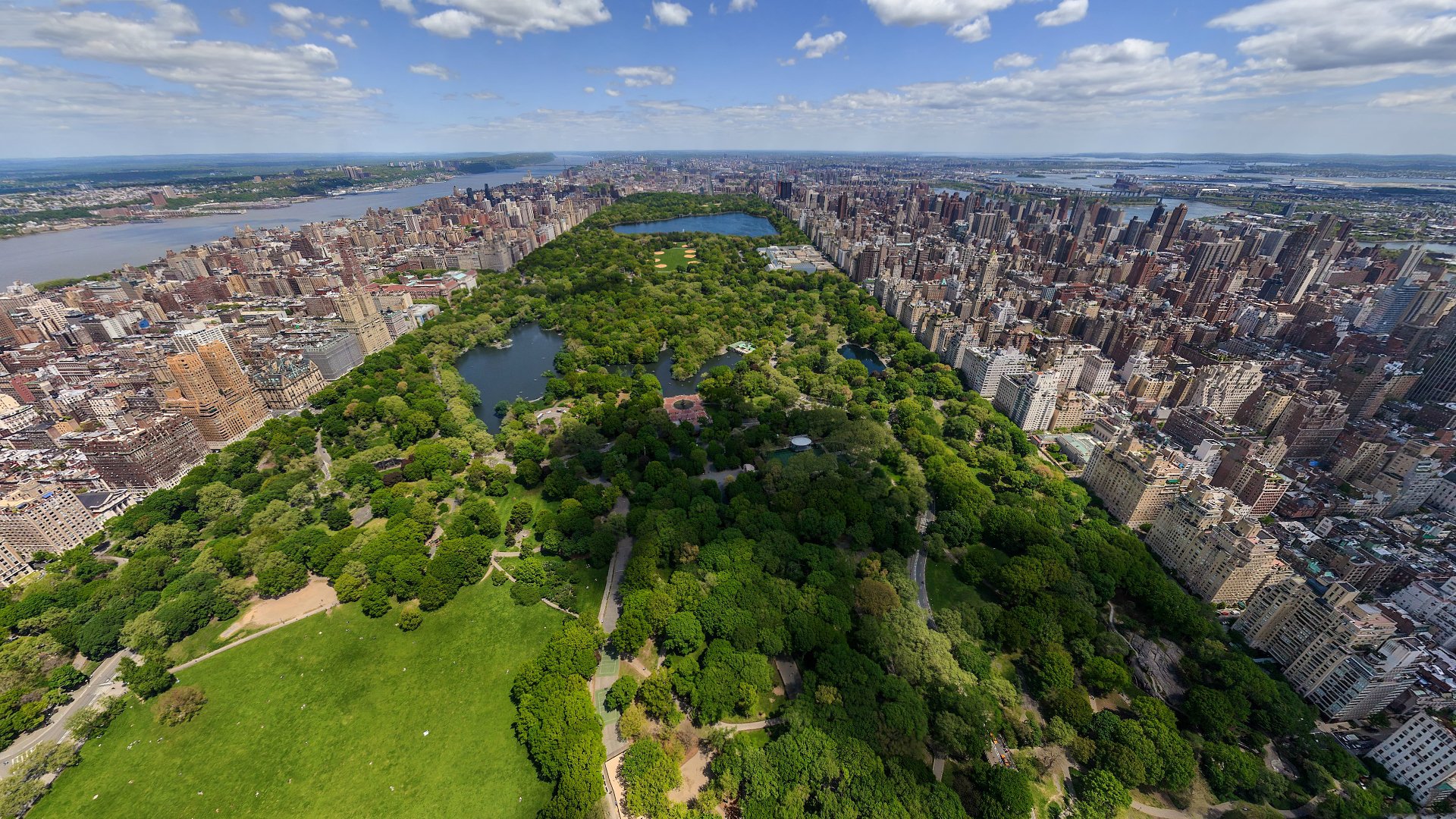 Aerial view of Manhattan showcasing the vast greenery of Central Park surrounded by the city's dense skyline, captured in HD for a desktop wallpaper background.