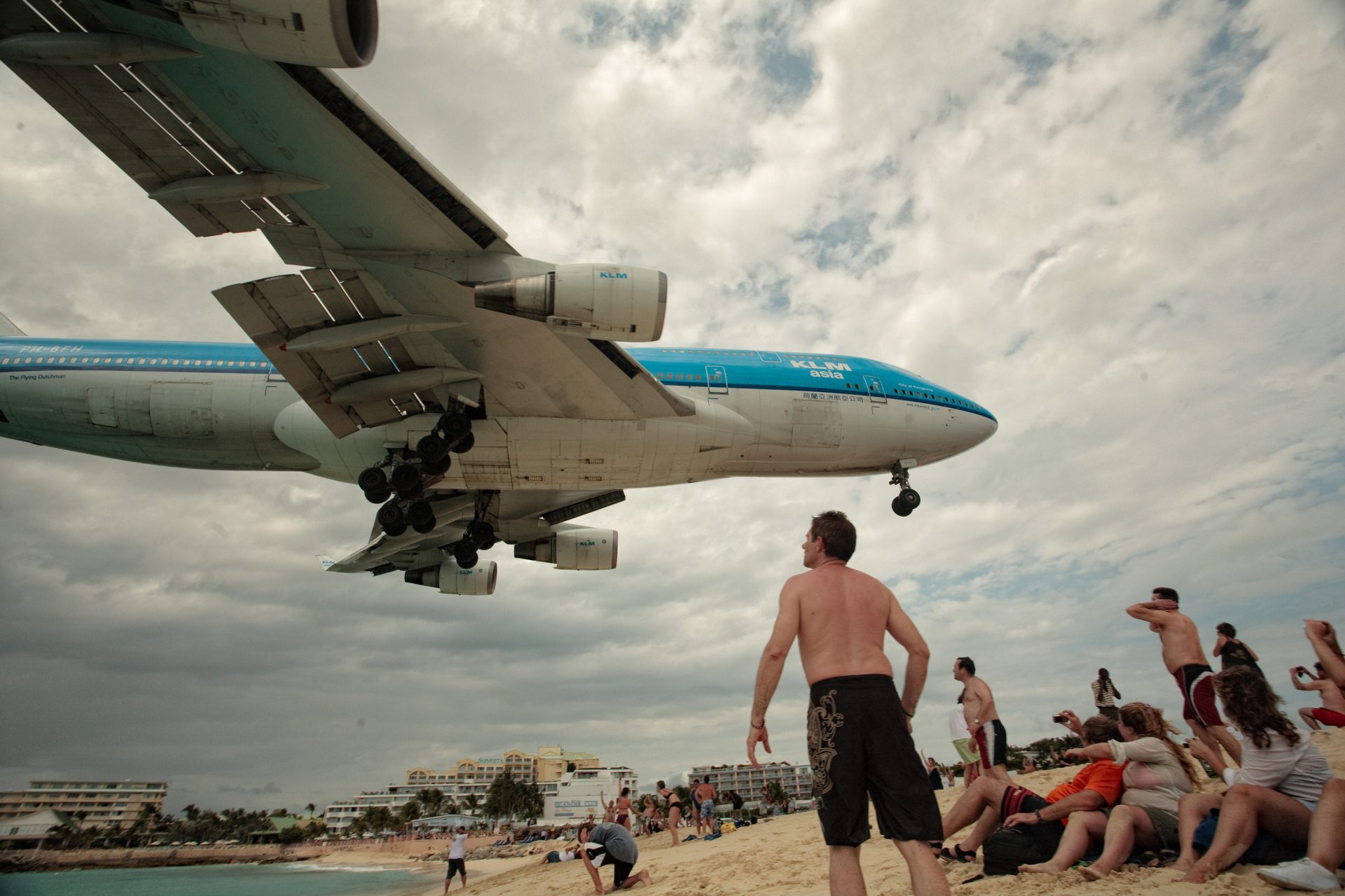 Beachgoers watching a low-flying airliner with landing gear down, engines in view — vehicle, aircraft. 2K Quad HD PC desktop wallpaper and background.