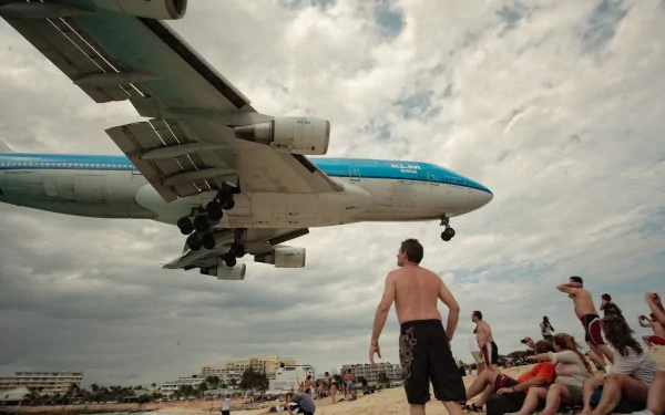 Beachgoers watching a low-flying airliner with landing gear down, engines in view — vehicle, aircraft. 2K Quad HD PC desktop wallpaper and background.
