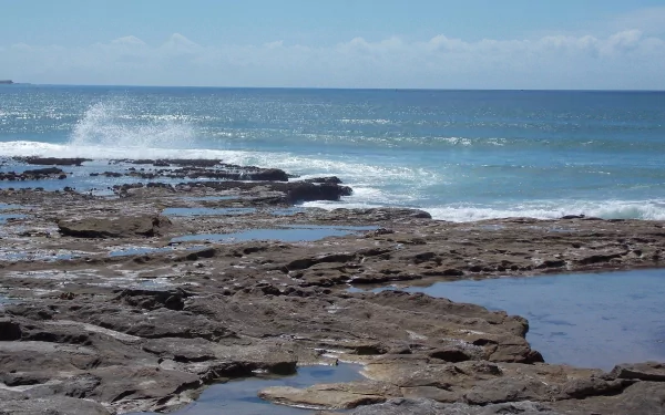 Seascape of Australia's Cronulla coast with waves breaking on rocky shore under a clear horizon, captured in HD ocean photography for a desktop wallpaper.