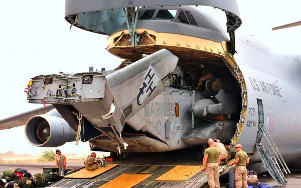 HD military desktop wallpaper featuring a Lockheed C-5 Galaxy cargo plane with its rear cargo door open and personnel loading equipment inside.