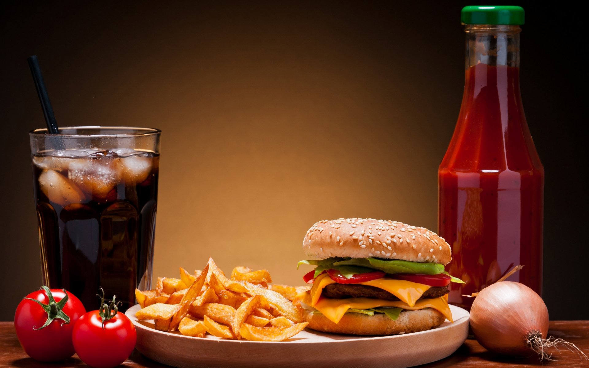 HD PC desktop wallpaper featuring a classic cheeseburger with lettuce, tomato, and pickles, served with golden fries, a glass of cola, and a ketchup bottle on a warm backdrop.