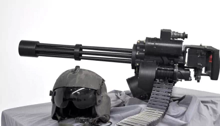 HD desktop wallpaper featuring an M134 Minigun alongside a tactical helmet and ammunition belt on a sleek gray background.