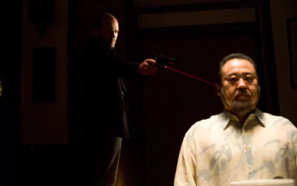 4K Ultra HD PC desktop wallpaper from the movie Parker: a bald action star aims a laser-sighted pistol at a seated man in a dim, tense interior.