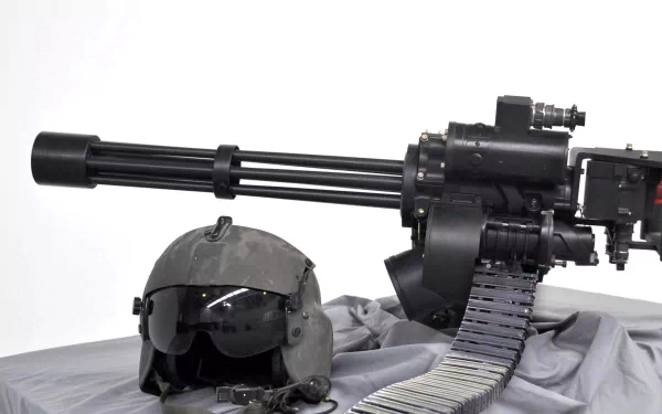 HD desktop wallpaper featuring an M134 Minigun alongside a tactical helmet and ammunition belt on a sleek gray background.