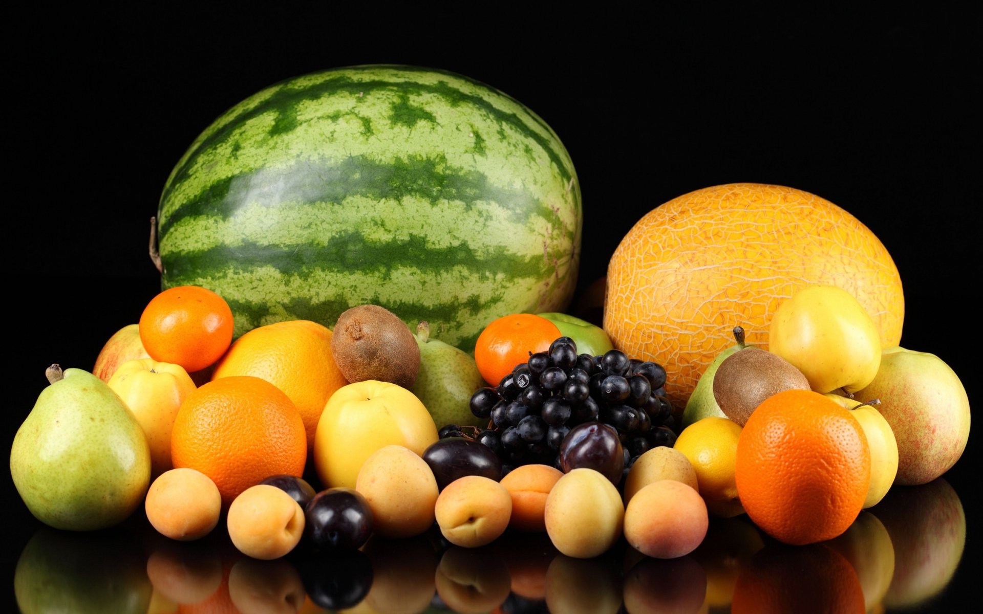 HD PC desktop wallpaper featuring a vibrant assortment of fresh fruits, including watermelon, cantaloupe, grapes, pears, and oranges, arranged on a reflective surface.