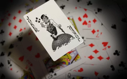 A captivating HD desktop wallpaper featuring a Joker card in focus, surrounded by an array of playing cards, creating a visually engaging man-made design.