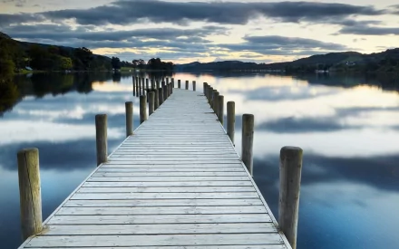 HD PC desktop wallpaper featuring a serene man-made wooden pier extending over calm water under a cloudy sky.