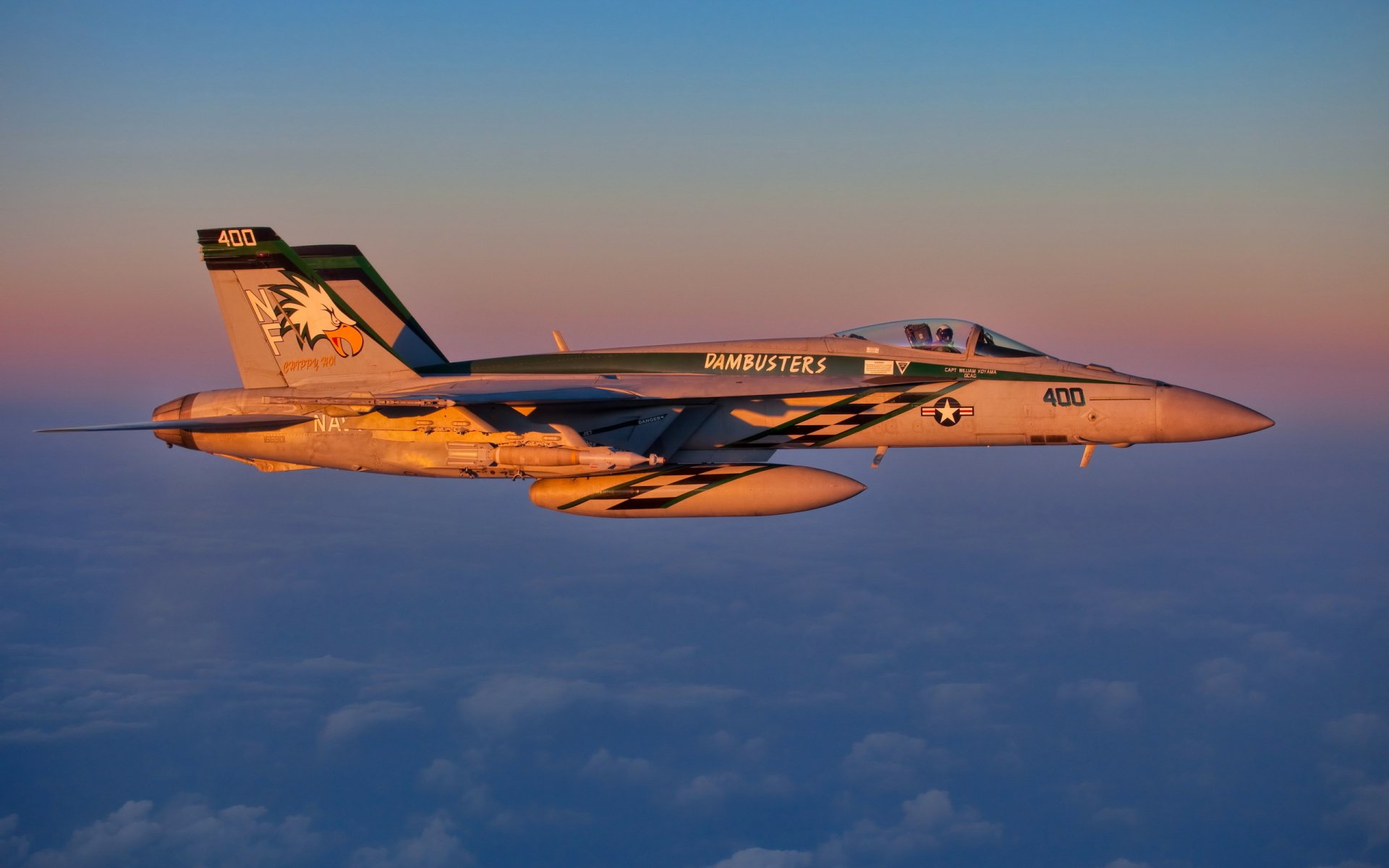 HD desktop wallpaper featuring a military Boeing F/A-18E/F Super Hornet flying above the clouds during sunset.