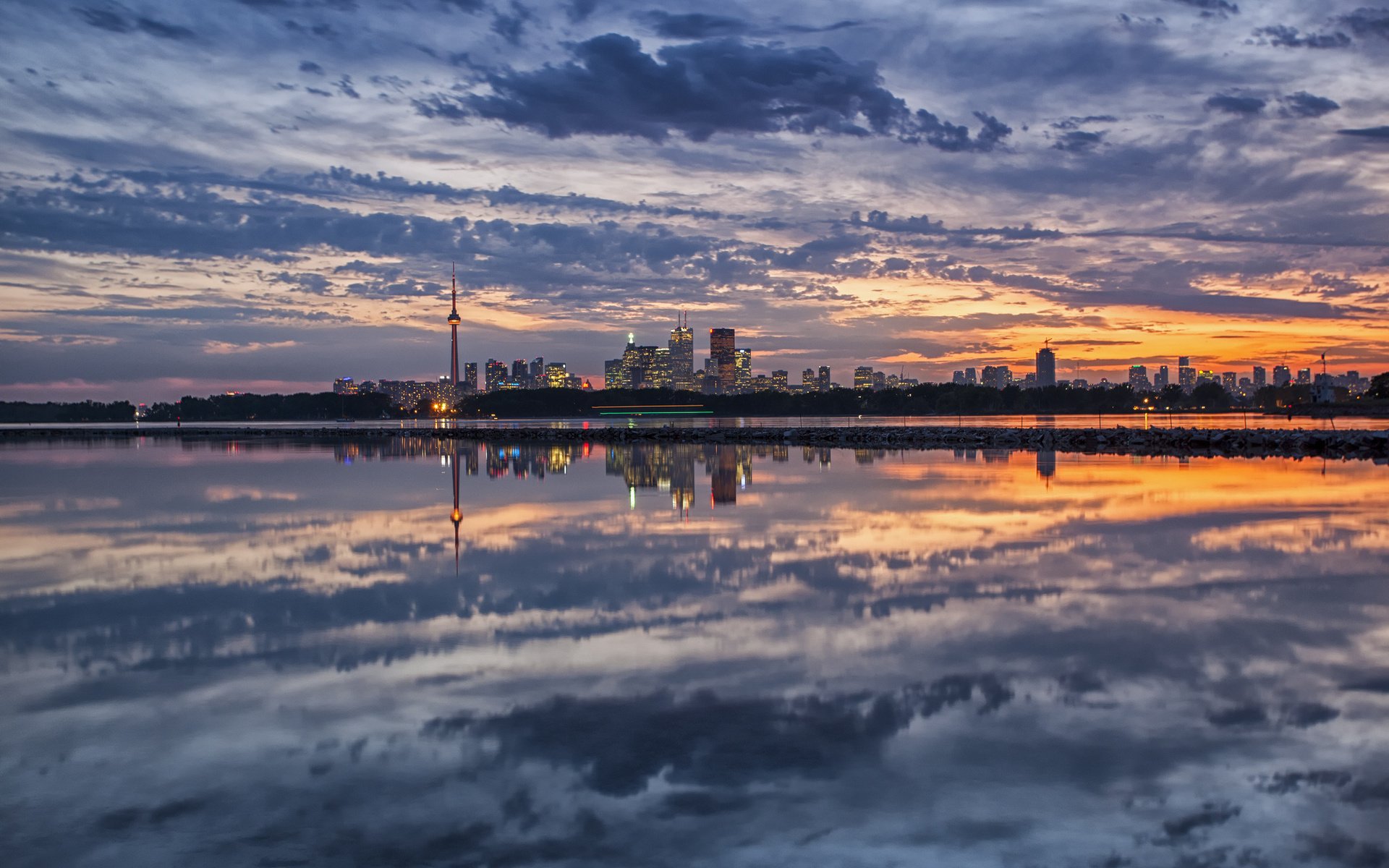HD photography of a city skyline at sunset reflected perfectly on calm water, creating a stunning and serene PC desktop wallpaper background.