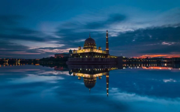 HD desktop wallpaper of the Putra Mosque at dusk, showcasing its religious architecture reflected in calm waters under a dramatic twilight sky.