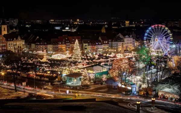 HD desktop wallpaper showing a vibrant, man-made Christmas market at night with festive lights, a large decorated tree, and a brightly lit Ferris wheel.
