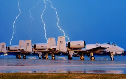 HD military desktop wallpaper featuring a row of Fairchild Republic A-10 Thunderbolt II aircraft on the tarmac with lightning striking in the background.