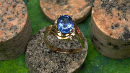 HD PC desktop wallpaper showing a man-made gold ring with a blue gemstone and small diamonds on textured cork discs over a green background.